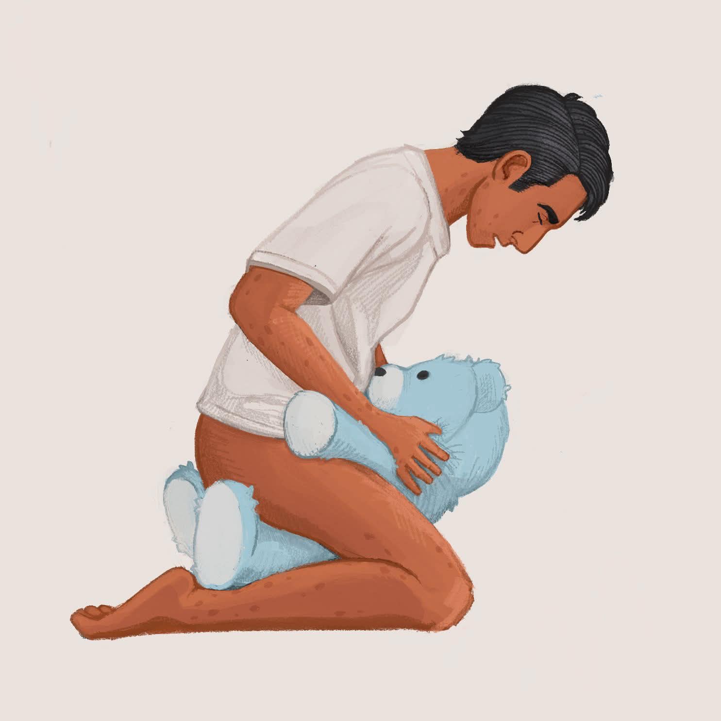 Jon wearing only a white t-shirt holding a blue teddy bear between his legs